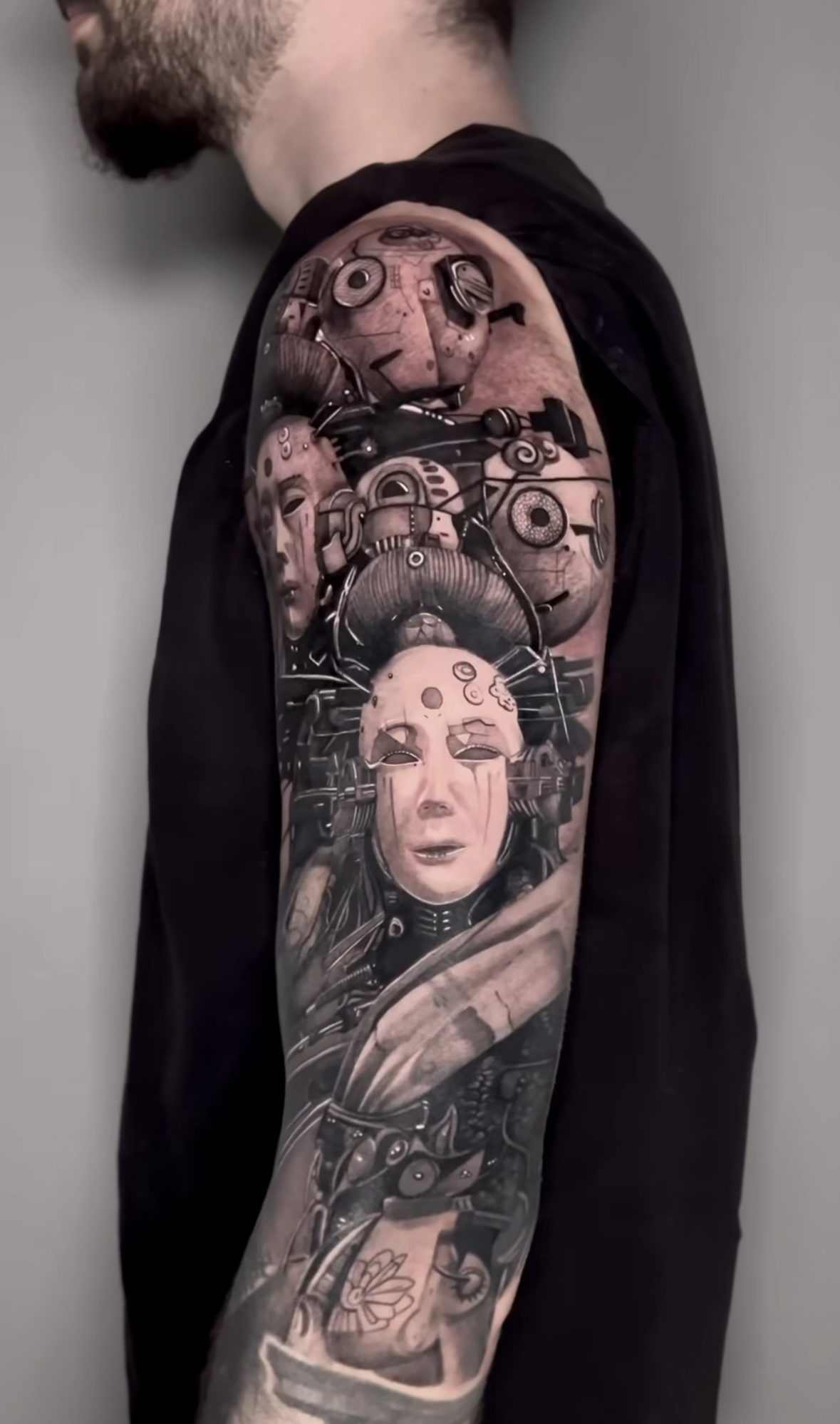 Full sleeve with a porcelain mask and mechanical details, black and grey realism tattoo by Ruby Ink