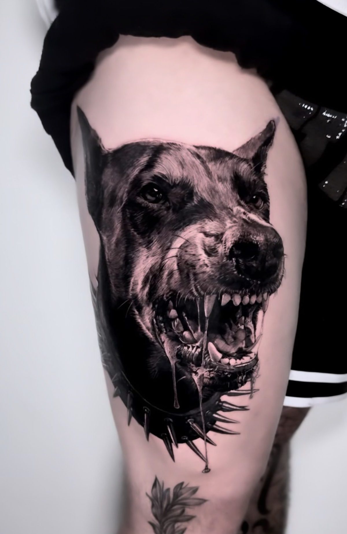 Snarling dog on the thigh, black and grey realism tattoo by Ruby Ink