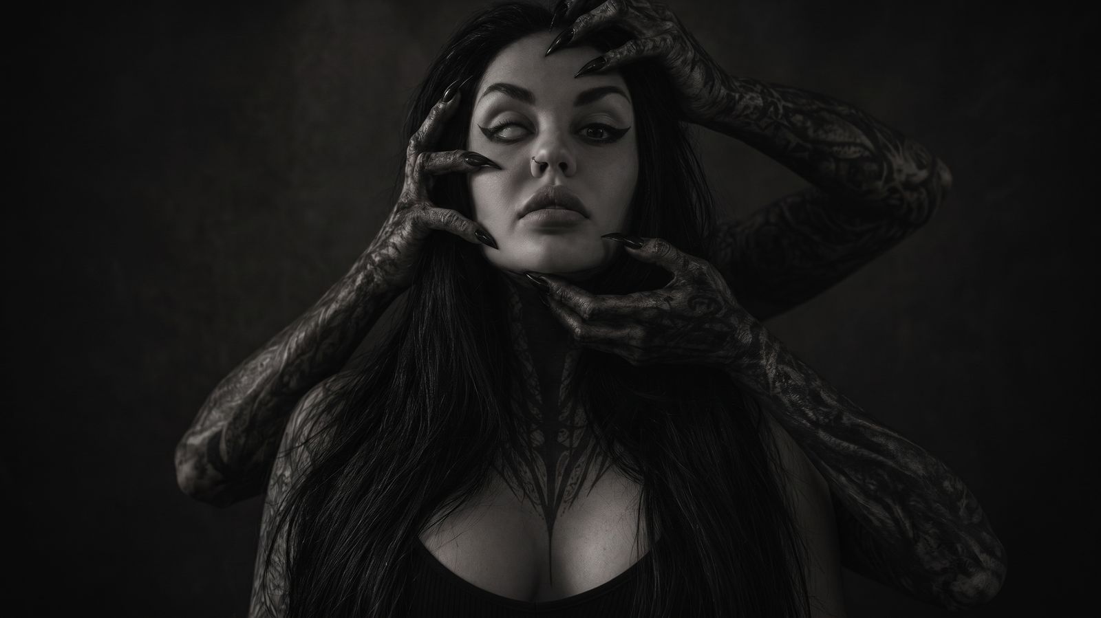 Ruby Ink, portrait of the tattoo artist in studio light with tattooed hands gripping her face