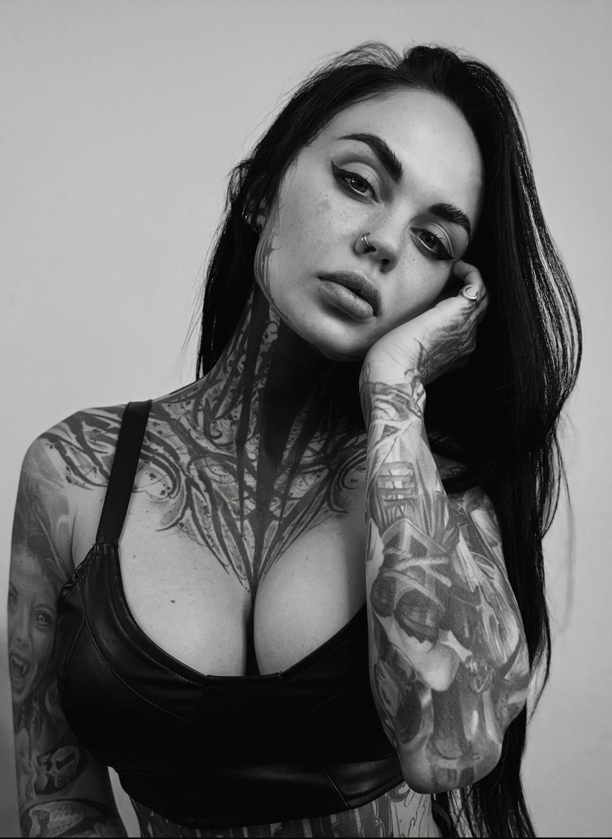 Black and white portrait of tattoo artist Ruby with tattooed neck and arms